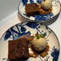 Dessert van brownie met vanille-ijs en karamel op blauw-witte borden met bloemdecoratie