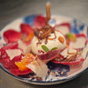Elegant opgemaakt dessert met een bol roomijs, geserveerd op een sierlijke blauw-witte porseleinen schaal met bloemmotief