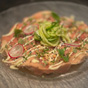 Elegant opgemaakt gerecht met een roze basis, geserveerd op een doorschijnend grijs bord