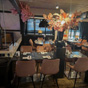 Sfeervol restaurant met zwarte tafels, roze stoelen en een grote opvallende bloemdecoratie in een zwarte vaas